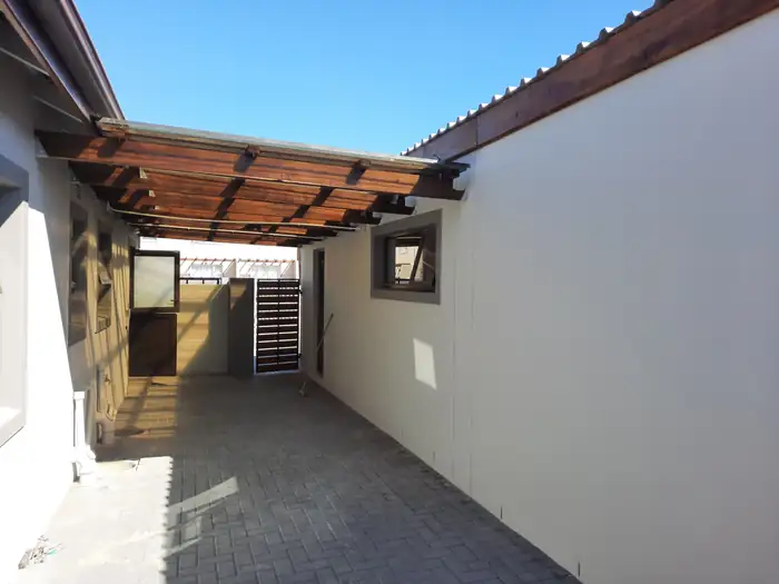 The covered walkway down the side of the house under its timber pergola