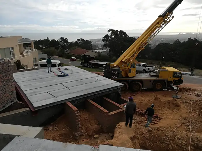 A crane lifting precast slab panels over the site at House Chapman