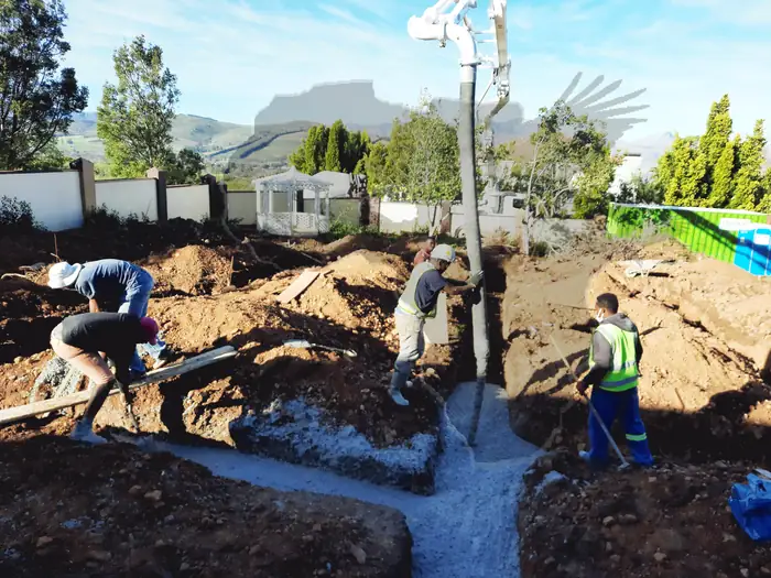 The team casting foundations at House Hillcrest with the mountains behind the site