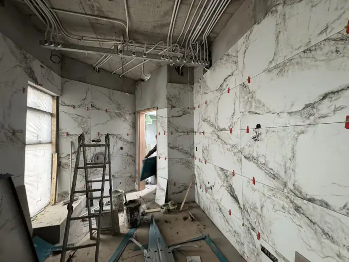 Large format slab cladding being set out on an interior wall